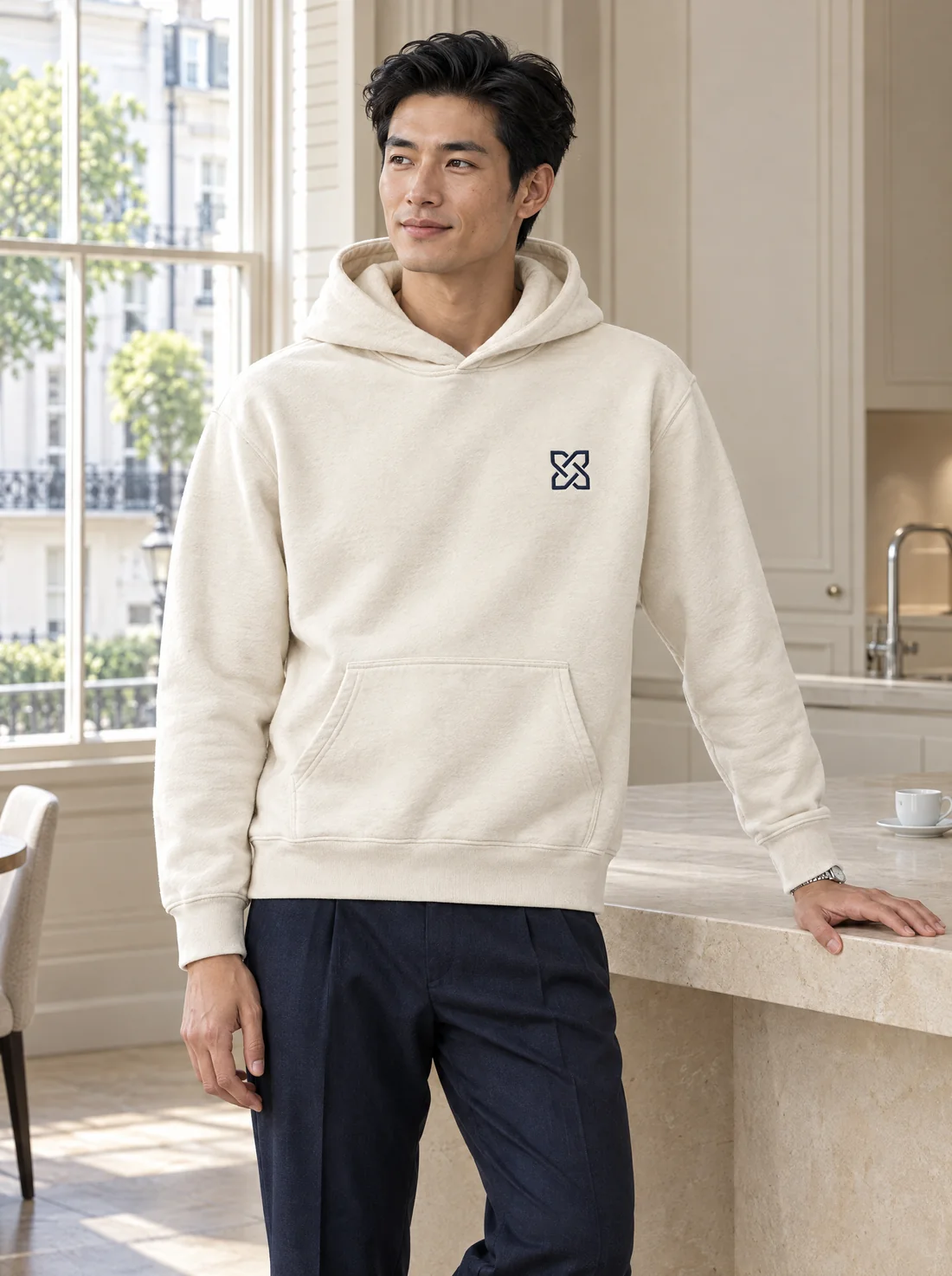 The cream Dolvero Desk Hoodie styled with navy trousers in a London home